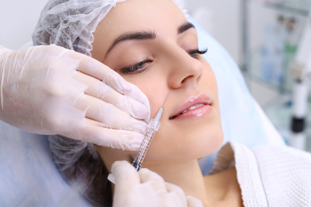 Woman having facial filler injected