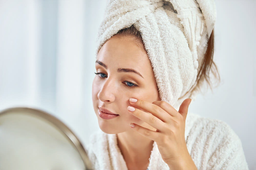 Woman looking at skin in mirror