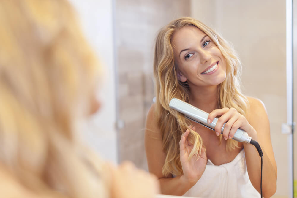 Woman curling hair with flat iron