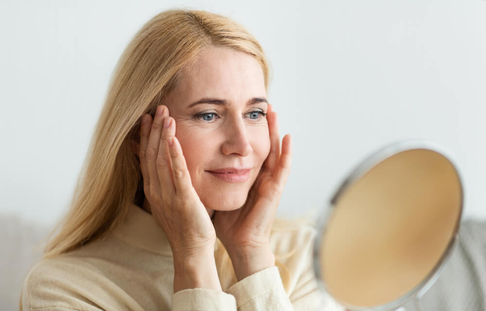 Woman looking at skin in mirror