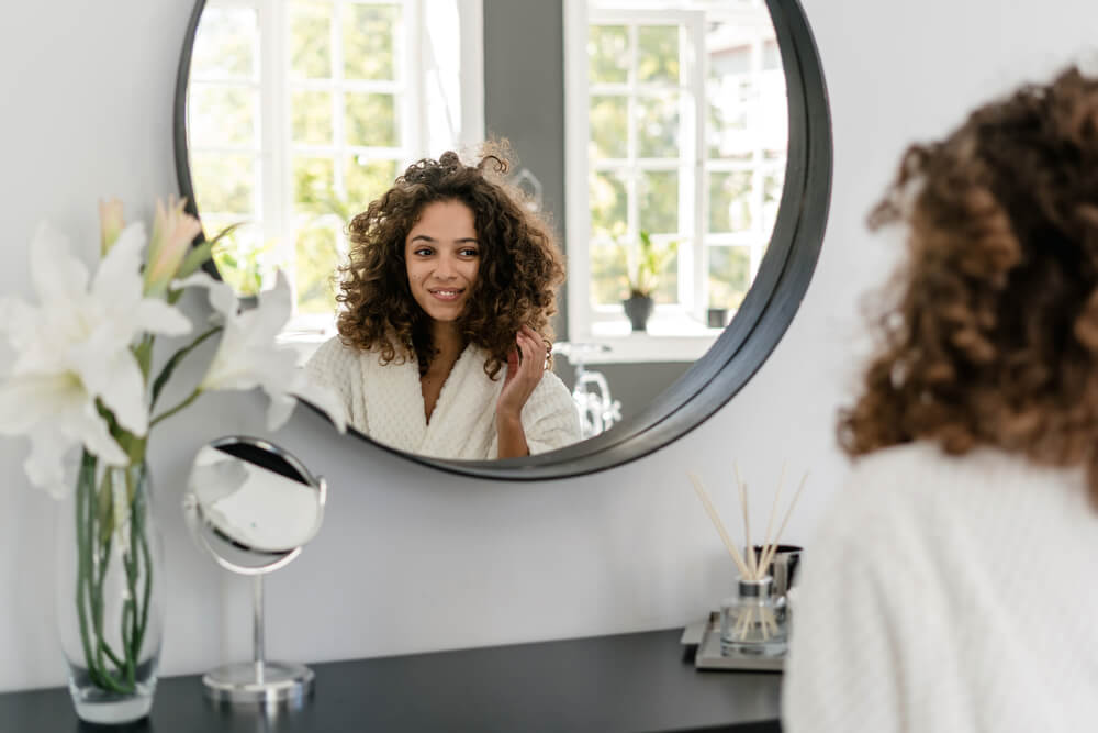 Woman looking at hair in mirror