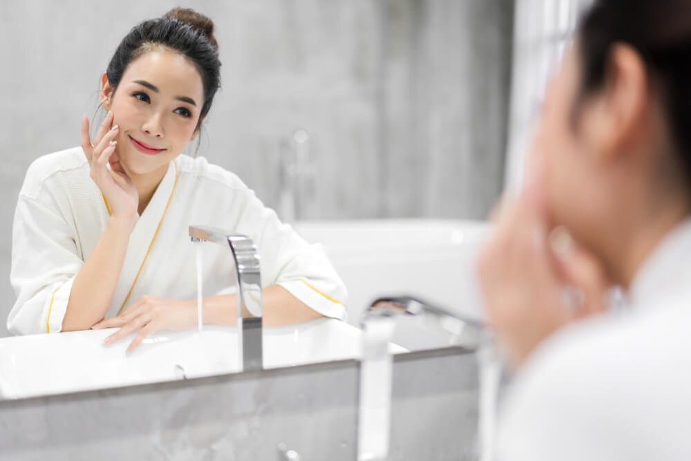 Woman looking at skin in mirror