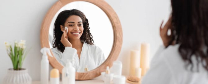 woman looking in mirror doing skincare